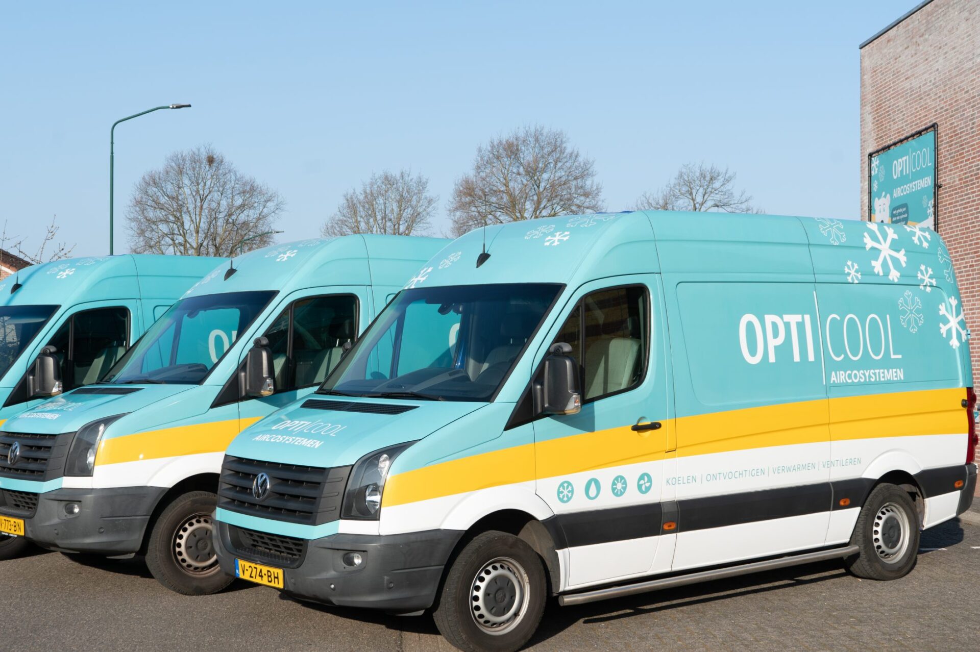 Drie bedrijfsbussen van Opti-Cool staan naast elkaar op straat.